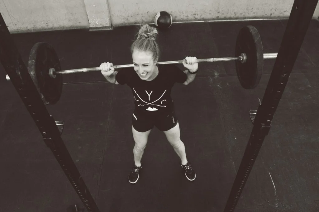 girl in red shirt and white panty holding red barbell